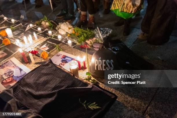 Flowers and candles are placed among pictures of journalists at a vigil in lower Manhattan on November 6, 2023 in New York City. The vigil is held to...