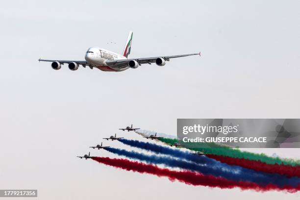 Aermacchi MB-339 trainer aircraft of the Fursan al-Emarat aerobatics team release smoke as they fly over with an Emirates Airbus A380-861 jetliner...