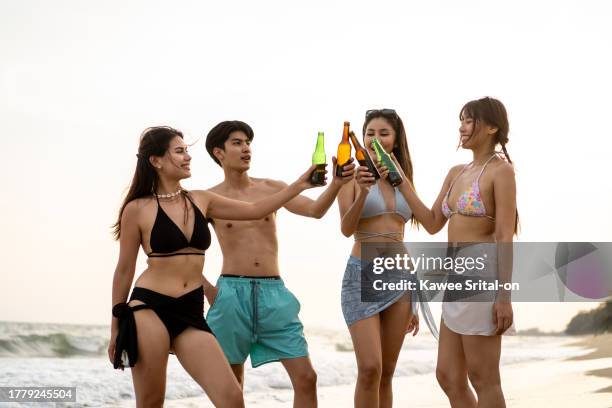 group of asian young man and woman having party on the beach together. attractive friends feeling happy and relax while standing at seaside enjoy holiday vacation trip in tropical sea island. - lagerphone stock pictures, royalty-free photos & images