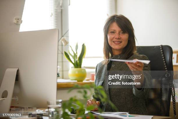 encantadora mujer de negocios sonriendo a la cámara y entregándole un documento - business person handing over a letter fotografías e imágenes de stock