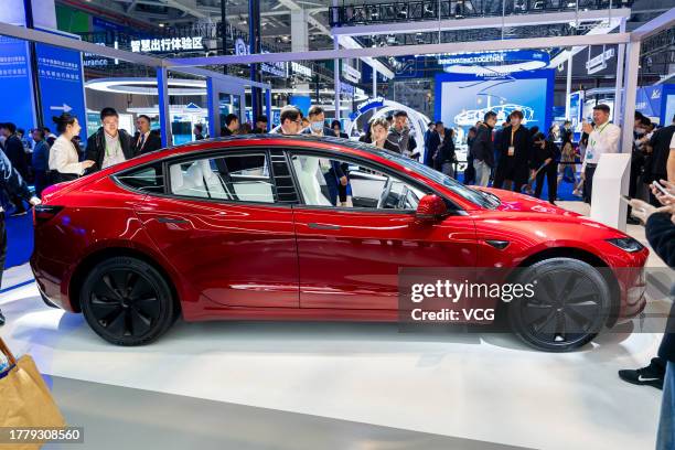 People look at a Tesla Model 3 sedan at the Tesla booth during the sixth China International Import Expo at the National Exhibition and Convention...