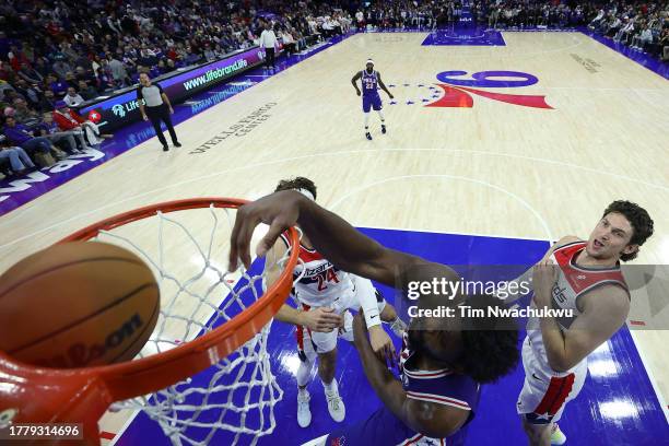 Joel Embiid of the Philadelphia 76ers dunks between Corey Kispert and Mike Muscala of the Washington Wizards during the third quarter at the Wells...