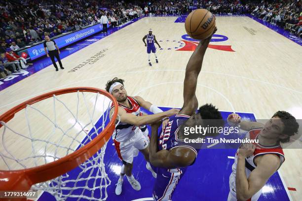 Joel Embiid of the Philadelphia 76ers dunks between Corey Kispert and Mike Muscala of the Washington Wizards during the third quarter at the Wells...