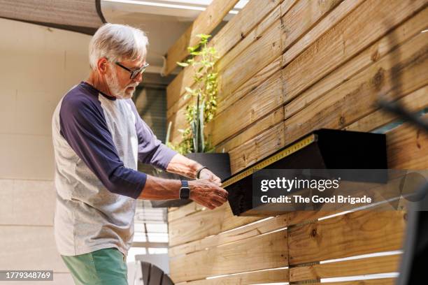 senior man measuring planter in back yard - handyman stock pictures, royalty-free photos & images