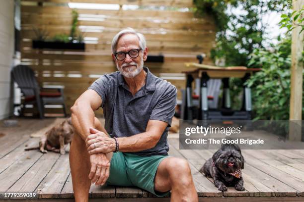 retired senior man sitting on back deck with dog - endast en pensionärsman bildbanksfoton och bilder