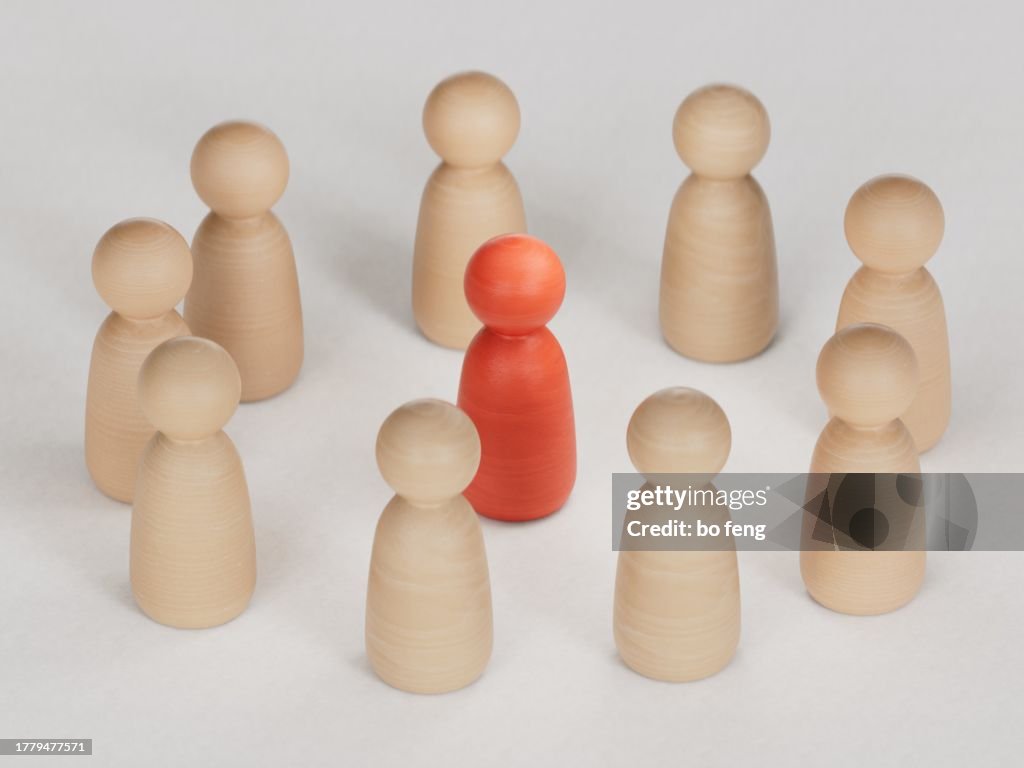 Red human figure surrounded by a circle of people. Leader Boss and leadership. Cooperation and teamwork. Outcast, hated opponent, criminal. Conviction. Discrimination and violence.