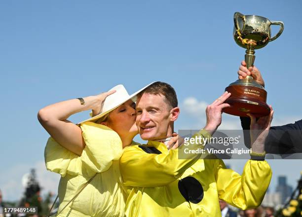 Mark Zahra is kissed by wife Elyse Zahra while posing with the trophy after riding Without A Fight to win Race 7, the Lexus Melbourne Cup, during...