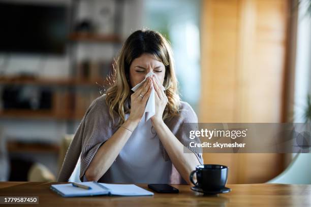 sick woman blowing her nose at home. - viral stock pictures, royalty-free photos & images