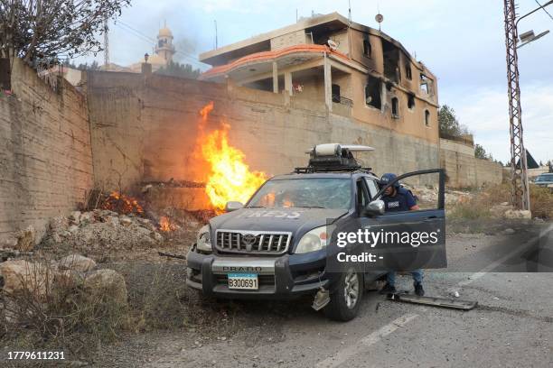 Flames erupt next to a press car following reported Israeli shelling in Lebanon's southern border village of Yaroun on November 13 amid increasing...