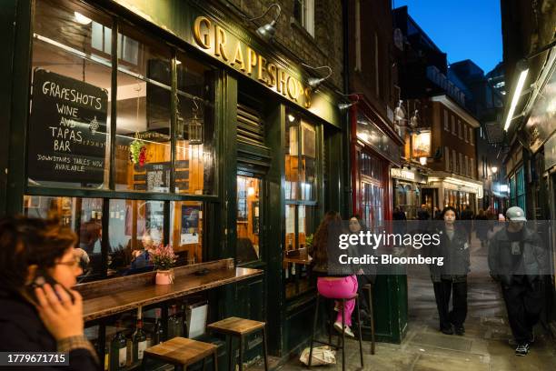 Commuters pass customers sitting outside the Grapeshots wine and tapas bar in the City of London, UK, Tuesday, Nov. 7, 2023. City center pubs, still...