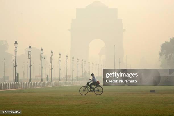 Man cycles past the Kartavya Path in front of the India Gate amid heavy smoggy conditions in New Delhi on November 7, 2023. Air quality in the...