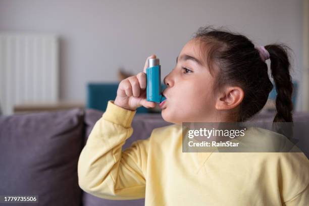 close-up da menina em uso de inalador para asma em casa - bronquite - fotografias e filmes do acervo