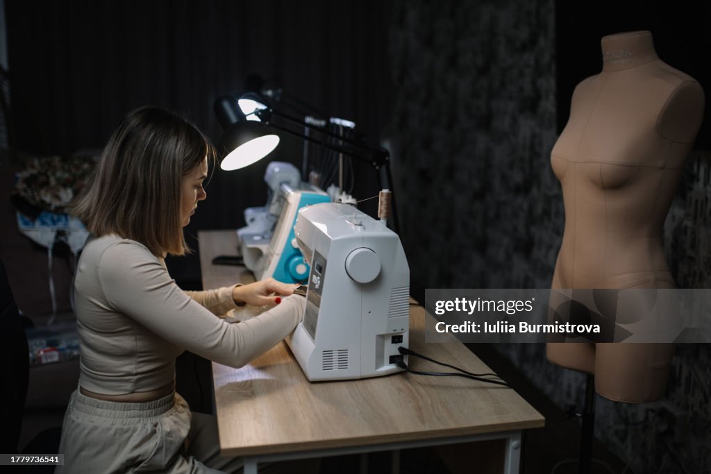 Dedicated craftswoman skillfully manipulates sewing machine, working till late night on client order