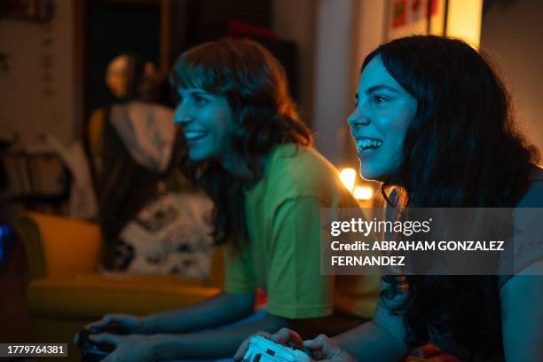 happy young women playing console at home at night - adrenaline junkie stock pictures, royalty-free photos & images