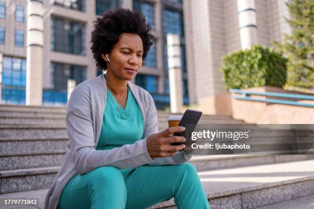 nurse sits outside to take a break. - in ear headphones stock pictures, royalty-free photos & images