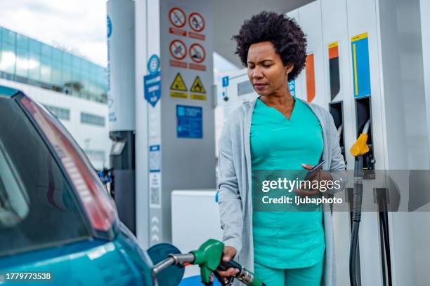 serious woman refueling car at gas station - filling stock pictures, royalty-free photos & images