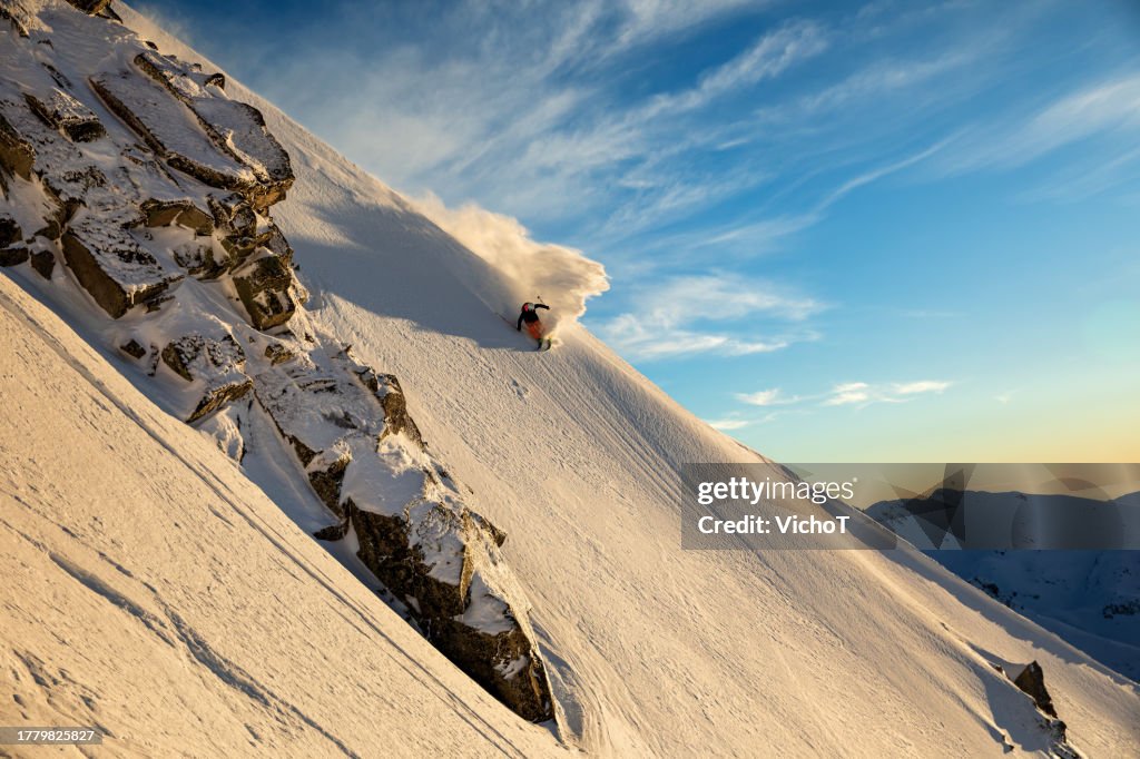 Back country skier riding down beautiful mountain slope at sunset
