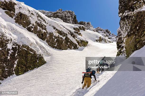 two back country skiers climbing a steep cliff in a sunny day - skier stock pictures, royalty-free photos & images