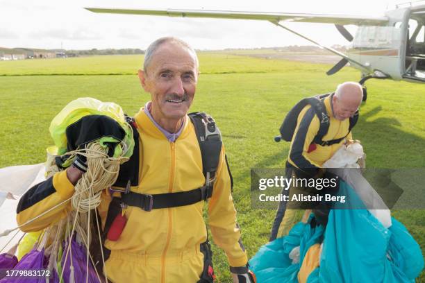 two senior male skydivers after completing a successful parachute jump - afterr stock pictures, royalty-free photos & images