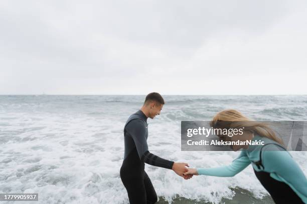 couple of surfers in their wetsuits - wetsuit stock pictures, royalty-free photos & images