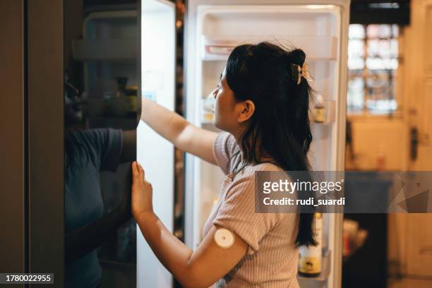 one woman, beautiful female using taking soda from refrigerator in kitchen. at home - glucose stockfoto's en -beelden
