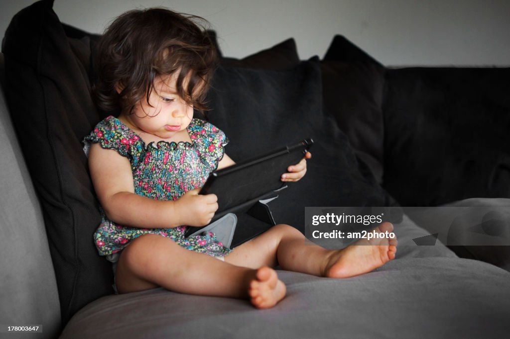 Toddler with a tablet in the sofa