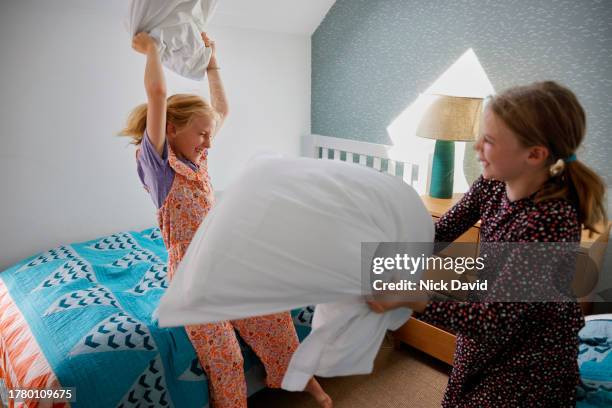 two girls having a pillow fight in their bedroom - thier stock pictures, royalty-free photos & images