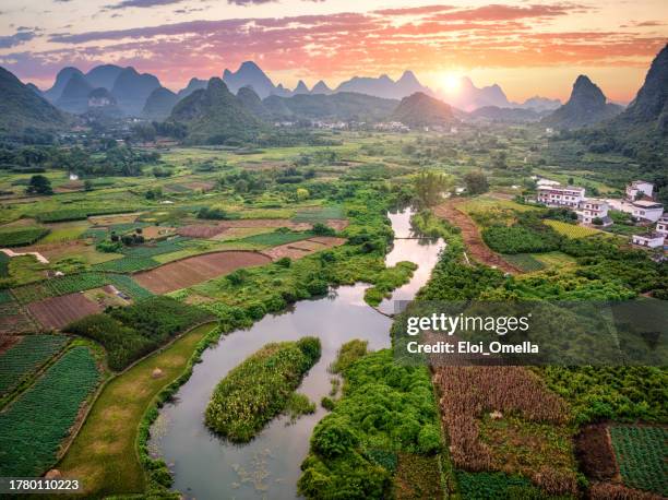 aerial view of river flowing through lush vegetation in cuiping during colorful sunset - yangshuo imagens e fotografias de stock