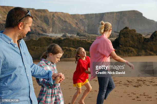 a young family walking together on the beach. - beach no people stock pictures, royalty-free photos & images