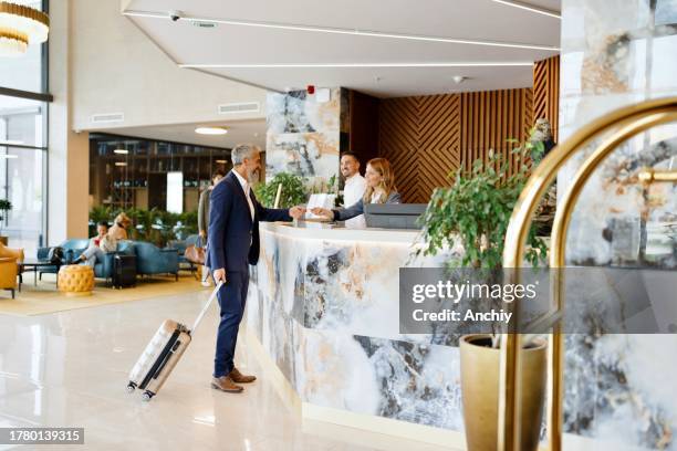 elegant gekleideter geschäftsmann, der aus dem hotel auscheckt - hotel stock-fotos und bilder