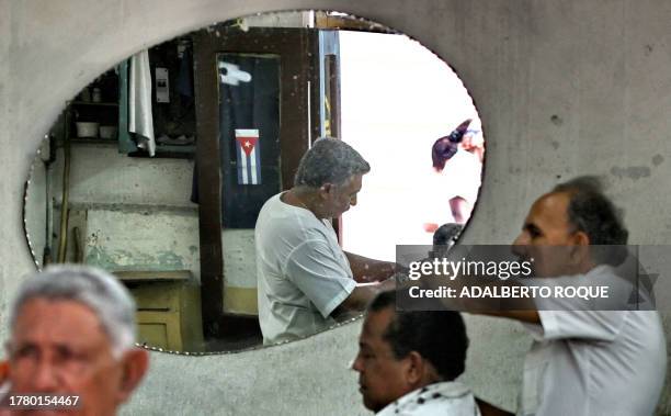 Cubans Pedro Veliz and his brother Andres Veliz work in their barbershop 14 January, 2007 in Santiago de Cuba, Cuba. The Cuban government prides...