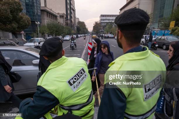 Young Iranian woman without wearing a mandatory headscarf, walks past an Iranian policeman in downtown Tehran, on November 13, 2023.