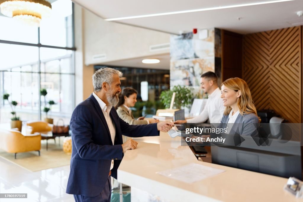 Hombre pagando algo con tarjeta de crédito en la recepción del hotel