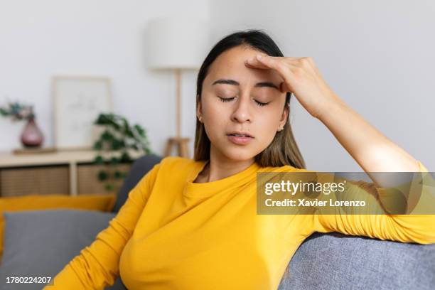 frustrated young woman feeling tired and worried about problem sitting on sofa at home. stressed or depressed girl having bad emotions. - complaining stock pictures, royalty-free photos & images