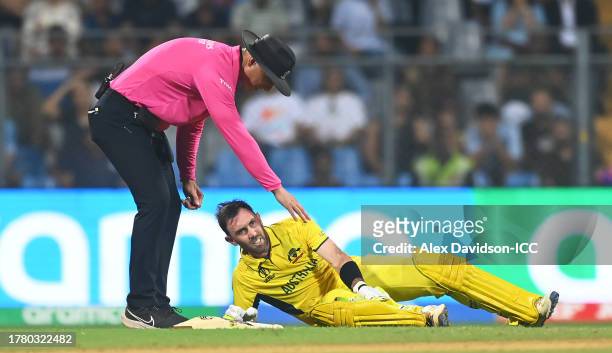 Glenn Maxwell of Australia receives medical attention as Match Umpire Alex Wharf looks on during the ICC Men's Cricket World Cup India 2023 between...