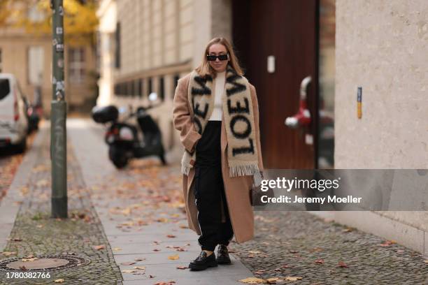 Sonia Lyson seen wearing Gucci black sunglasses, Loewe beige / black oversized fluffy wool logo scarf, Wolford cream white top, The Frankie Shop...