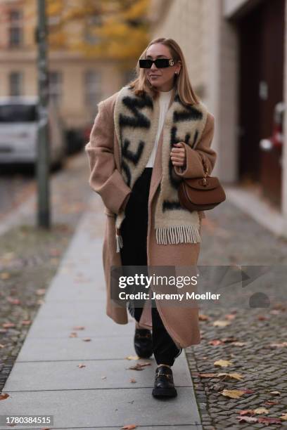 Sonia Lyson seen wearing Gucci black sunglasses, Loewe beige / black oversized fluffy wool logo scarf, Wolford cream white top, The Frankie Shop...