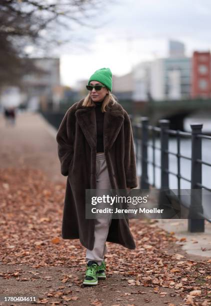 Sonia Lyson seen wearing Bottega Veneta green sunglasses, H&M green wool knit beanie, Zara black top, On Vacation beige jogger pants, Stand Studio...