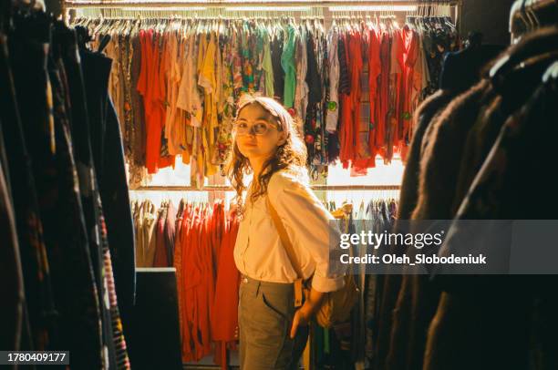 fröhliche frau kauft in secondhand-laden in berlin ein - kleiderstange stock-fotos und bilder