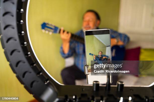 old man is playing his guitar to show it on his social networks - misses vlog stock pictures, royalty-free photos & images