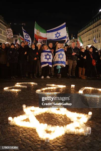 People gather at the Brandenburg Gate over candles in the form of a Star of David for an event to commemorate the victims of the October 7 incursions...