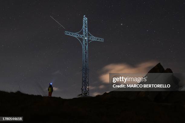 Leonid meteor streaks across the sky over the cross of San Bernardo Mount, near the village of Valmala in the Alps Region, northwestern Italy, on...