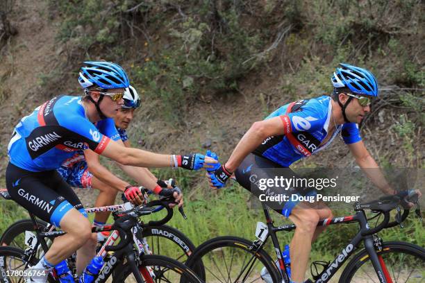 Rohan Dennis of Australia riding for Garmin-Sharp delivers beverages to teammate Christian Vande Velde of the USA riding for Garmin-Sharp during...