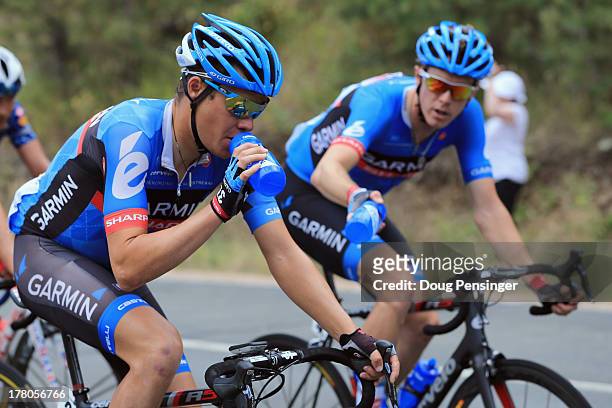 Rohan Dennis of Australia riding for Garmin-Sharp delivers beverages to teammate Tom Danielson of the USA riding for Garmin-Sharp during stage six of...