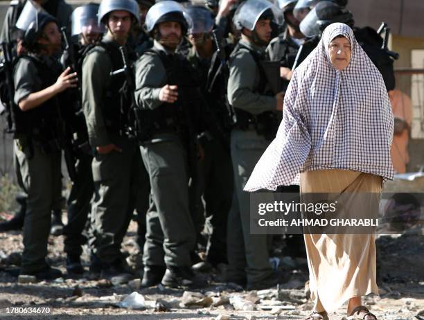 Woman walks past Israeli border policemen standing guard during the demolition of a house in the east Jerusalem Arab neighbourhood of Silwan on...