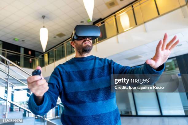 worker in the office with vr glasses, cyberspace experience at work. an office worker touching objects in the digital world and controlling with the controller in his hand, a businessman in 3d glasses interacting with virtual reality, dressed in a blue st - cyberspace stock pictures, royalty-free photos & images