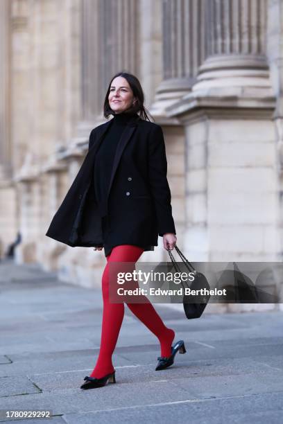 Alba Garavito Torre wears a black wool turtleneck pullover, a black mini skirt from Zara, red tights from Calzedonia, a black oversized blazer jacket...