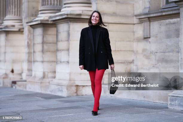 Alba Garavito Torre wears a black wool turtleneck pullover, a black mini skirt from Zara, red tights from Calzedonia, a black oversized blazer jacket...