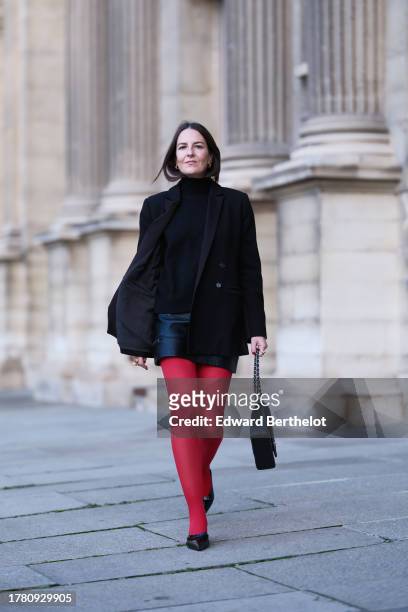 Alba Garavito Torre wears a black wool turtleneck pullover, a black mini skirt from Zara, red tights from Calzedonia, a black oversized blazer jacket...