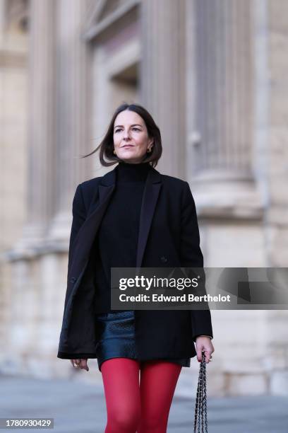 Alba Garavito Torre wears a black wool turtleneck pullover, a black mini skirt from Zara, red tights from Calzedonia, a black oversized blazer jacket...